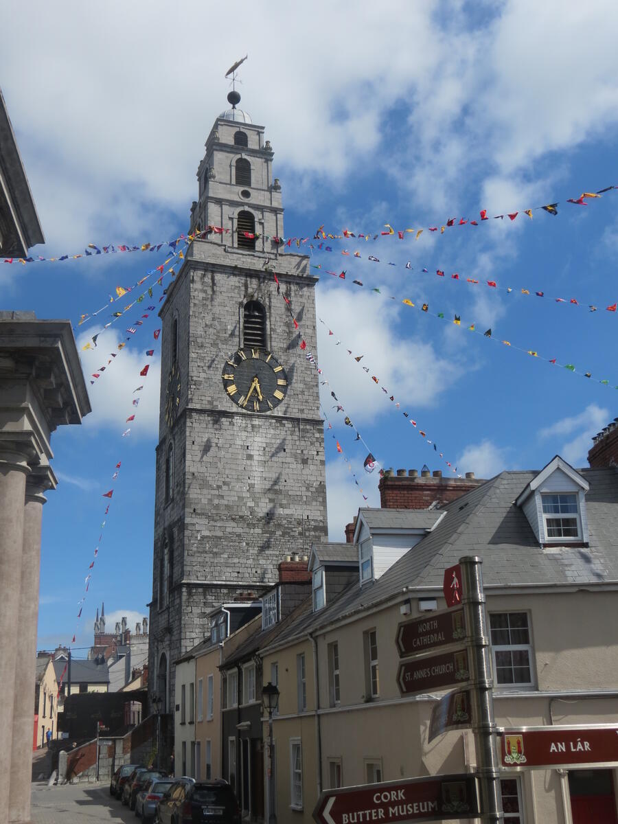 St Anne&rsquo;s Church and the Shandon Bells rising above rooftops in Cork City, with colourful bunting strung across the sky.
